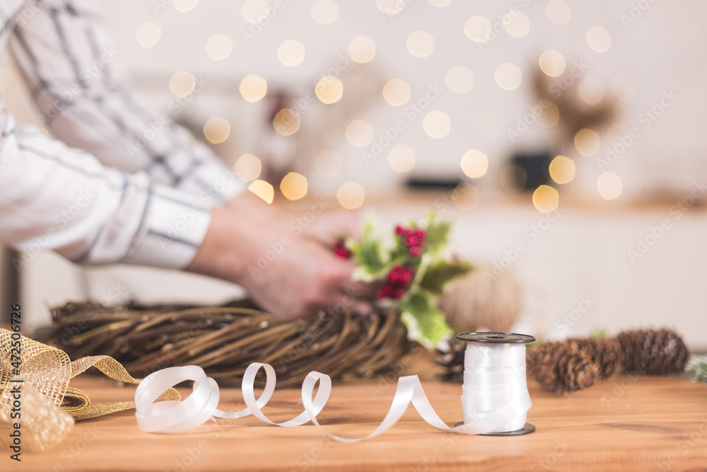 Woman artisan making Christmas holiday wreath on a table among by New Year's decor Woman artisan making Christmas holiday wreath on a table among by New Year's decor