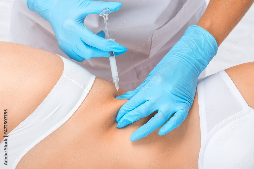 Fototapeta premium cosmetologist makes lipolytic injections to burn fat on the stomach and waist of a woman. Female aesthetic cosmetology in a beauty salon.Cosmetology concept.