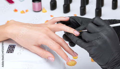 Coating nails with gel polish in the beauty salon. Professional care for hands.