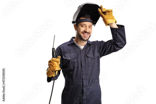 Young welder in a uniform and a shield on his head holding a welding machine