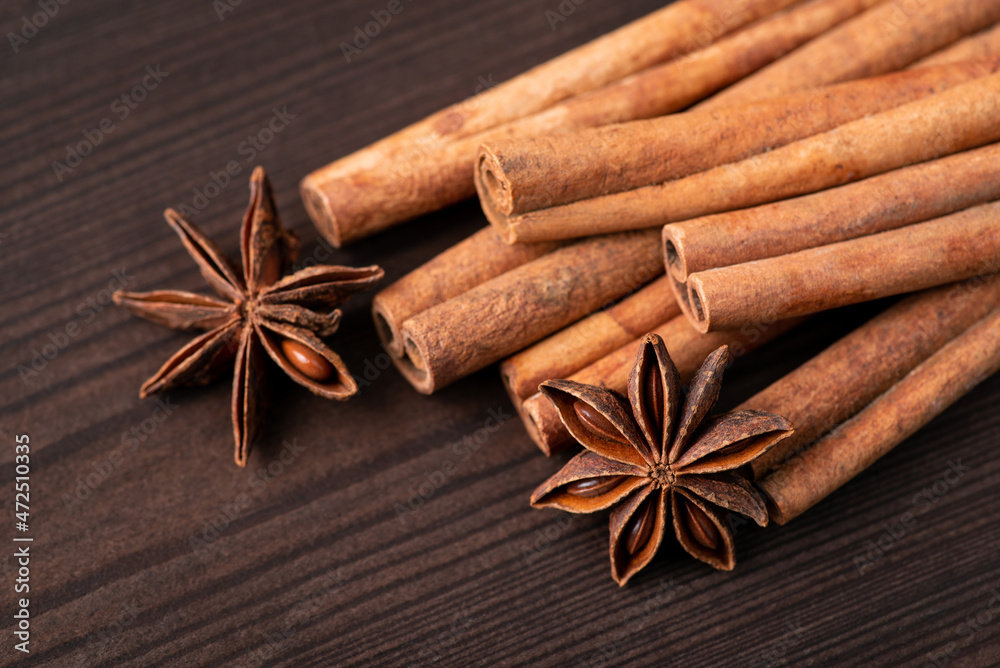 Close-up shot of cinnamon and some stars of anise against black wooden background. Cinnamon and star anise spices Close-up shot of cinnamon and some stars of anise against black wooden background. Cinnamon and star anise spices