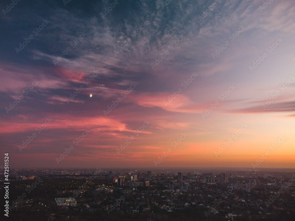Aerial scenic vivid colorful sunset clouds on epic skyscape with moon. Kharkiv city center, residential district streets in evening light