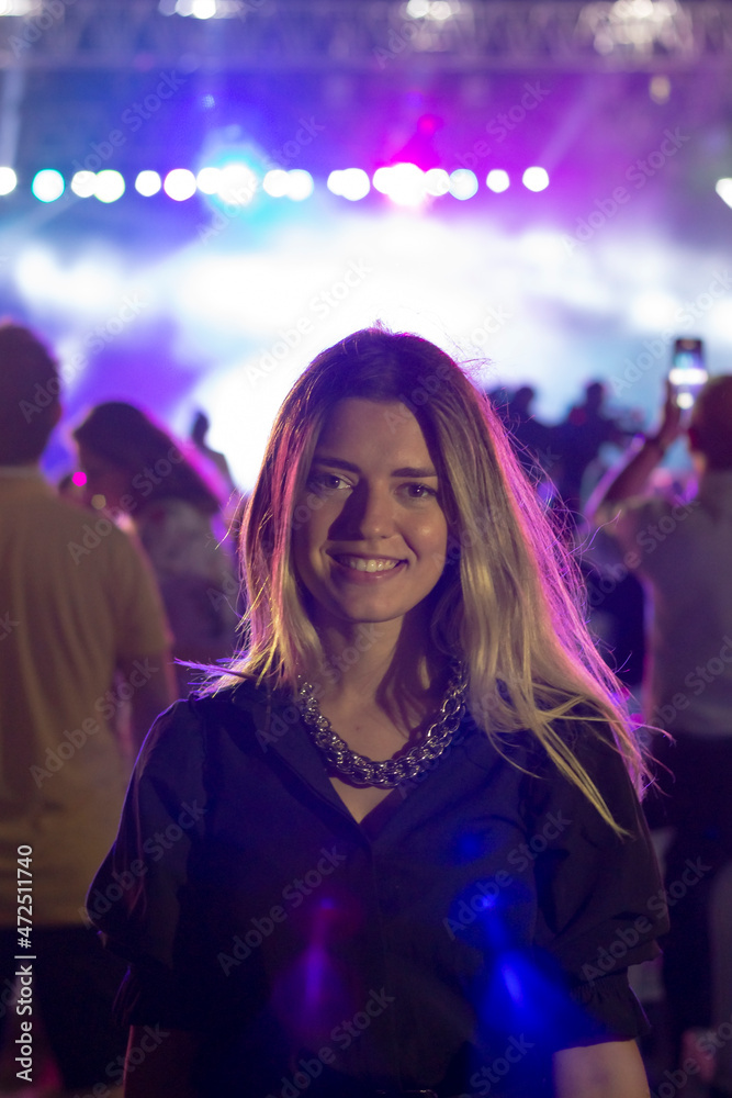 A girl laughing in concert area. There is purple light in there. Everyone taking photos. A girl laughing in concert area. There is purple light in there. Everyone taking photos.