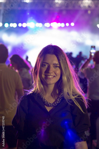 A girl laughing in concert area. There is purple light in there. Everyone taking photos. 