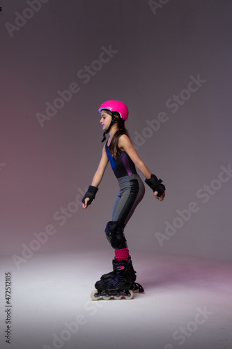 young skater athlete with pink helmet and protective gear training for competition in a studio.