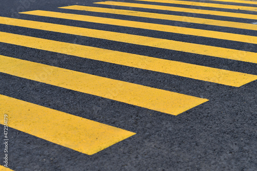 New temporary pedestrian crossing is marked with yellow lines on fresh asphalt. Selective focus