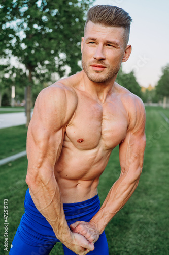 sporty muscled man with naked torso in a workout park