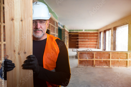 Builder with board in his h...