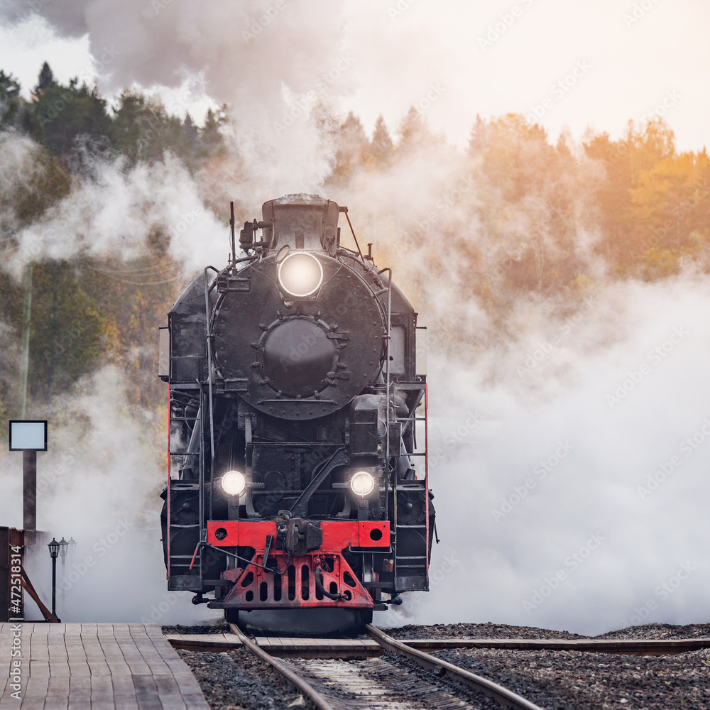 Retro steam train arrives to the station wooden platform.