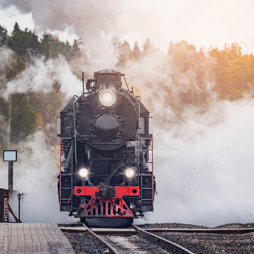 Retro steam train arrives to the station wooden platform.