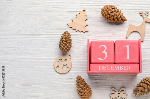 Calendar with date of New Year, pine cones and decorations on light wooden background photo