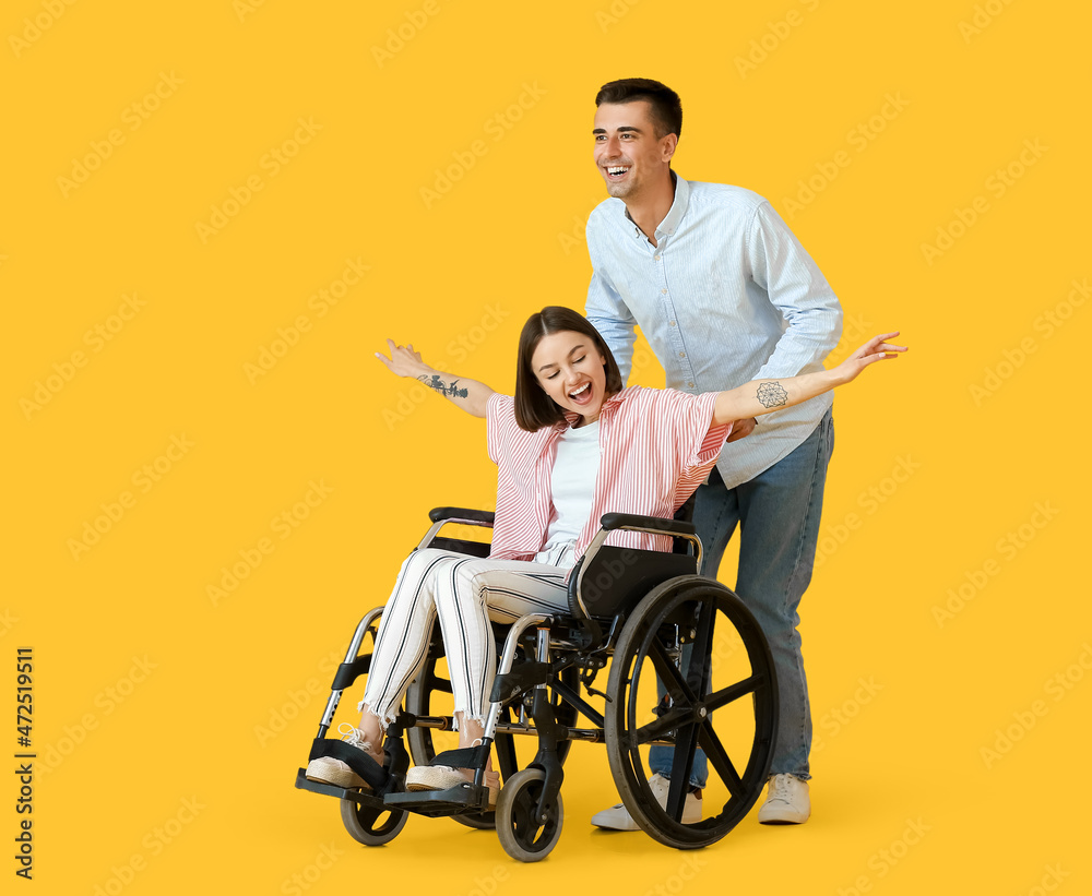 Young woman in wheelchair and her husband on color background