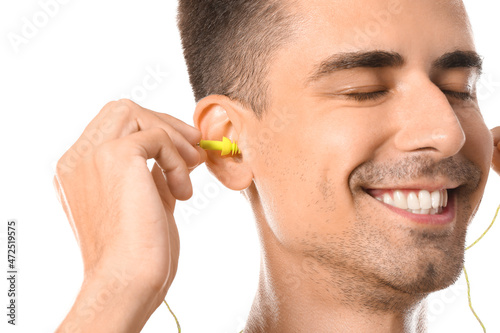 Photography Smiling young man putting earplugs on white background