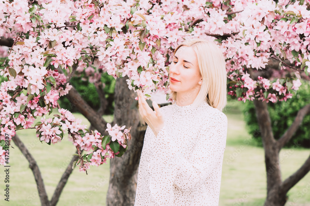 Young woman among the blossoming trees. Spring nature park or garden, flowering trees. Concept spring woman health Young woman among the blossoming trees. Spring nature park or garden, flowering trees. Concept spring woman health