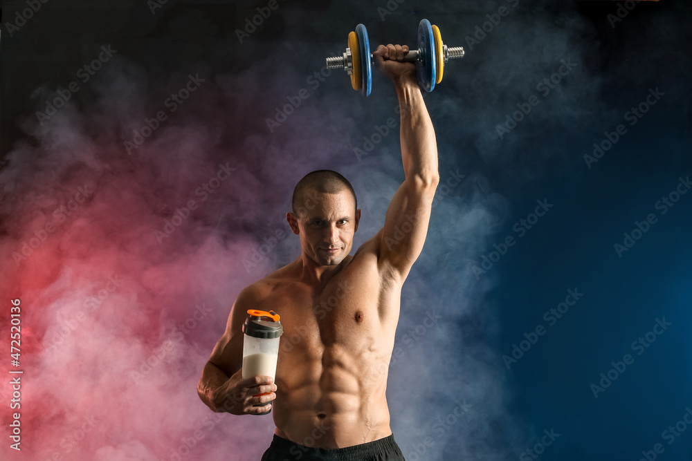 Obraz premium Male bodybuilder with protein shake and dumbbell on dark background