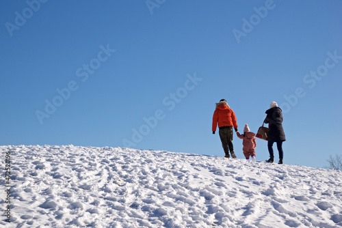 Happy family in outdoors - Father, mother and child are having fun on snowy winter walk in nature.