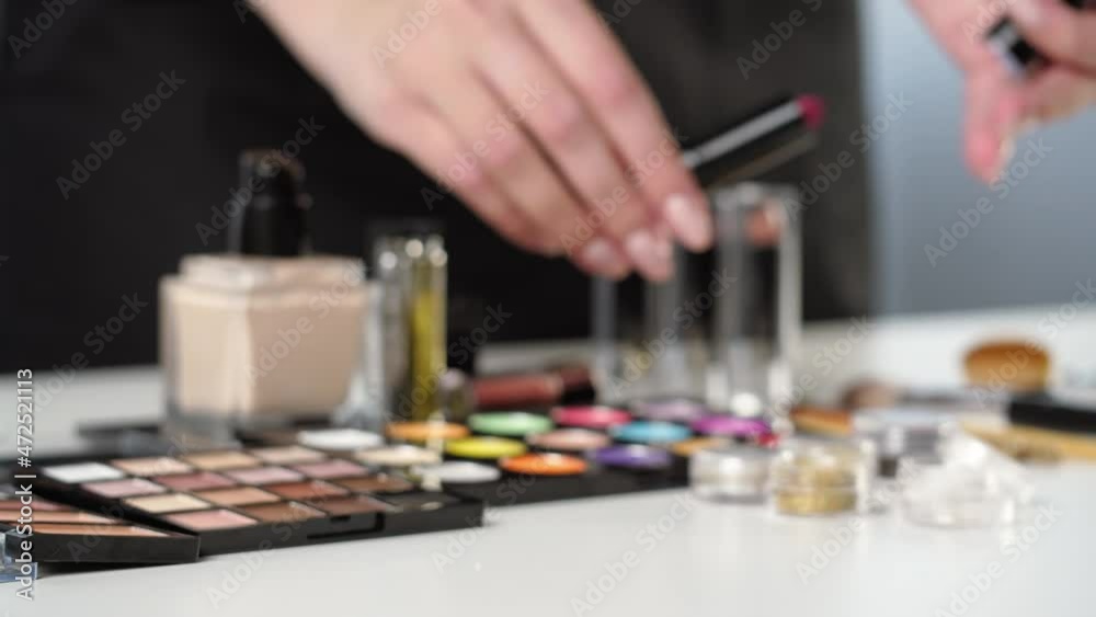 Opening lipstick close-up. Palette of shadows on white table. Visagiste professional set, beauty industry concept. Trying makeup products. Foundation and colorful eyeshadows on background. Opening lipstick close-up. Palette of shadows on white table. Visagiste professional set, beauty industry concept. Trying makeup products. Foundation and colorful eyeshadows on background.