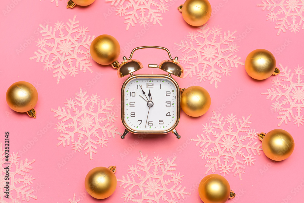 Composition with alarm clock and Christmas balls on pink background