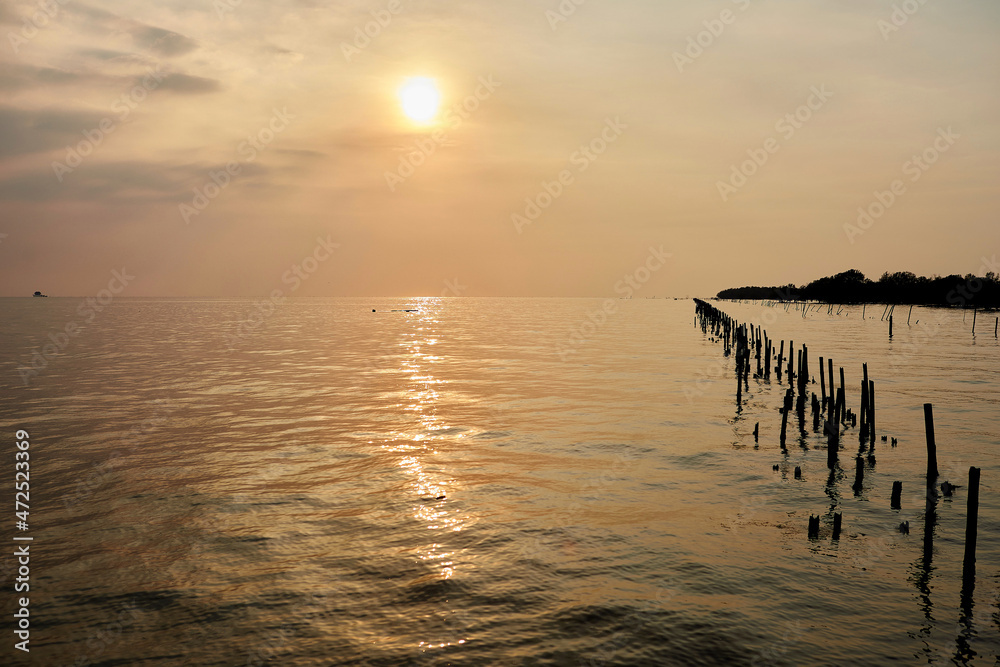 Obraz premium sunset over the sea with wooden post
