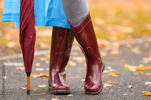 Young woman wearing gumboots in park on autumn day