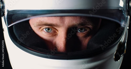 Man with strong blue eyes looking into the camera and closing the helmet visor in 4k slow motion close up of face photo