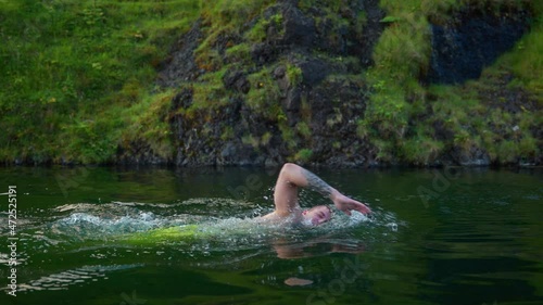 Man Swims In The Famous Outdoor Pool Of Seljavallalaug In Southern Iceland. wide shot photo