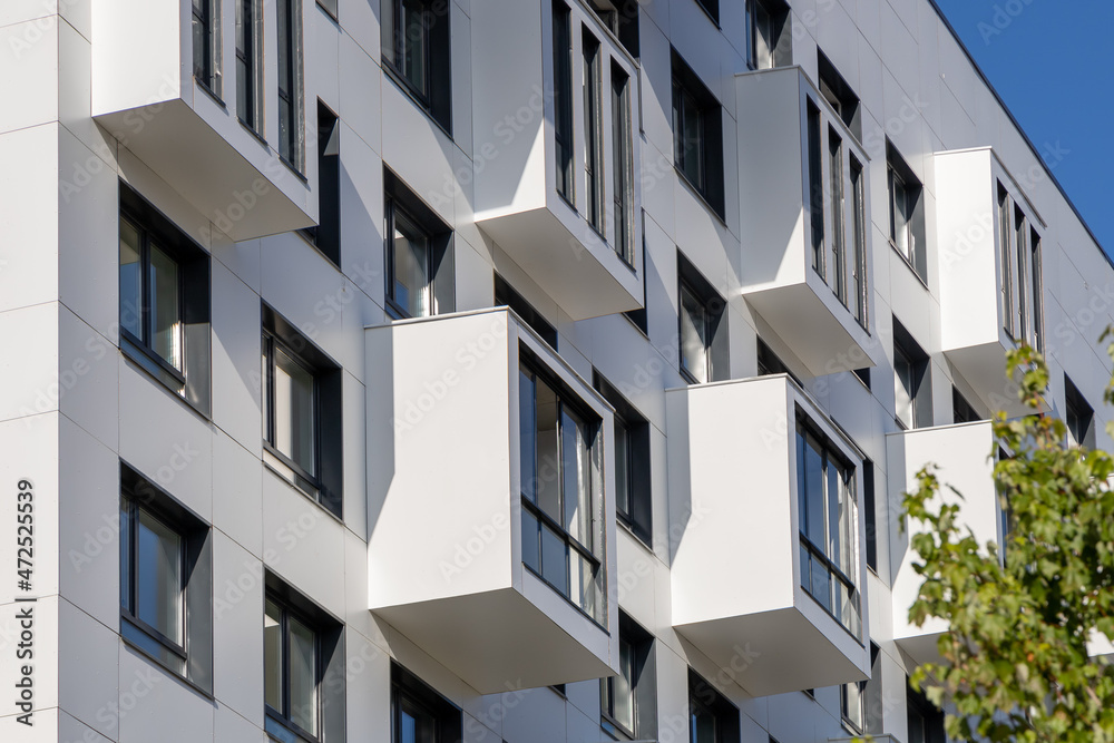 Compact balconies on the white facade of the condominium. Multi-storey apartments. Small living space Compact balconies on the white facade of the condominium. Multi-storey apartments. Small living space