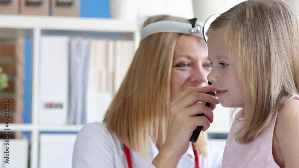 Ent doctor with frontal reflector looking at ear of little girl using otoscope 4k movie slow motion Ent doctor with frontal reflector looking at ear of little girl using otoscope 4k movie slow motion