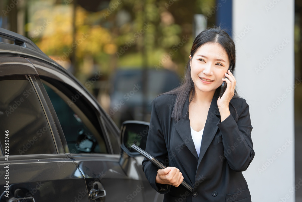 Businesswoman holding digital tablet and talking on the phone at the car park. Businesswoman holding digital tablet and talking on the phone at the car park.