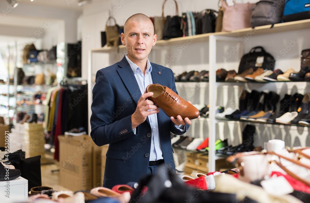 Cheerful man looking for new classic brown shoes at shopping mall