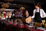 Attractive woman waiter receiving order from guest in fashionable restaurant. High quality photo