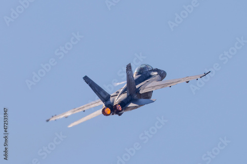 Tail view of a F-18 Hornet in a high G maneuver, with condensation streaks at the wing roots and afterburners on