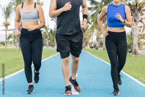 Group of three young adult runners at a public running trail no face front view