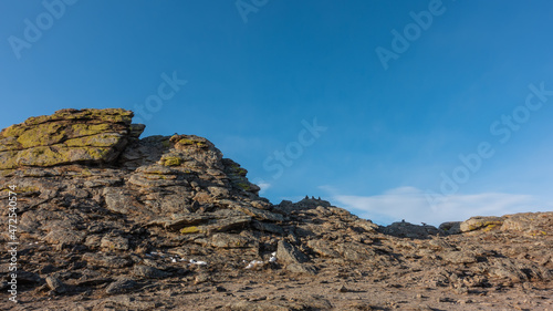 A picturesque granite rock against a clear blue sky. Yellow lichens grow on the cracked slopes. A sunny day. Olkhon Island. Siberia