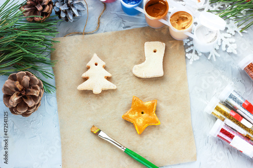 Fototapeta Naklejka Na Ścianę i Meble -  a brush with gold paint paints a Christmas star, DIY toys for the New Year, creative decoration for a Christmas tree made of salt dough