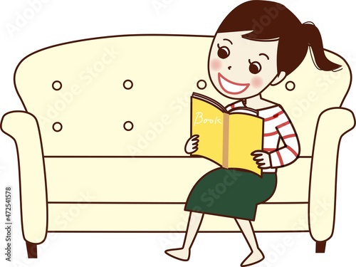 ソファーで本を読む笑顔の若い女性。
