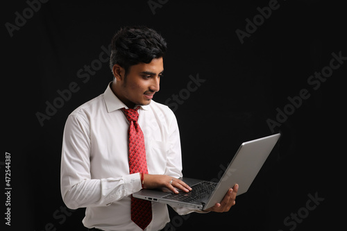 Young indian banker or officer using laptop