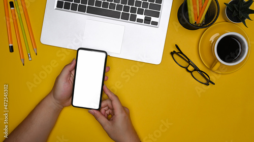 Fotografia, Obraz Overhead view man using smart phone at creative workspace.