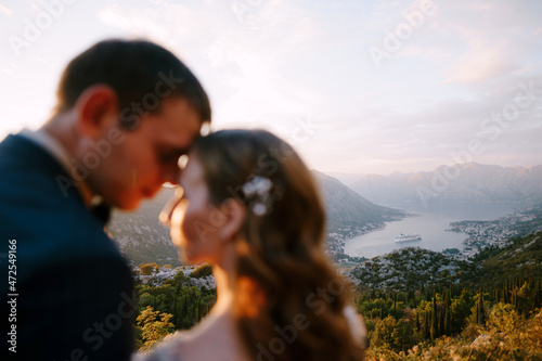 Bride and groom touch their foreheads against the background of Kotor Bay. Close-up