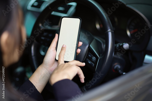 Close-up of a woman or businesswoman using smartphone in her car.