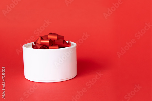 white gift box with red ribbon bow on red background. present for Christmas, new year, valentine day