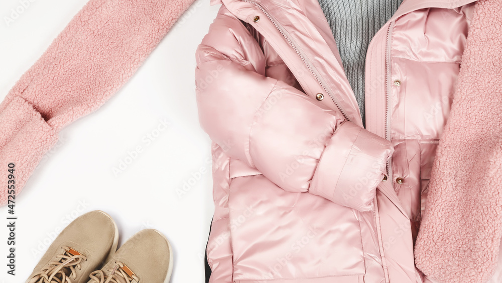 Women's pink down jacket, scarf, sneakers on a white background, top view. Autumn, winter women's clothing fashion concept