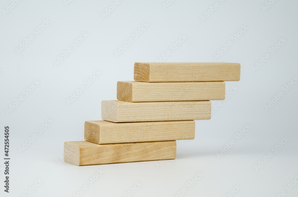 Wooden bars are stacked in the form of steps. Blank blocks of wood on top of each other. The concept of business, interaction, career growth. Template for design, space for text and symbols. Wooden bars are stacked in the form of steps. Blank blocks of wood on top of each other. The concept of business, interaction, career growth. Template for design, space for text and symbols.