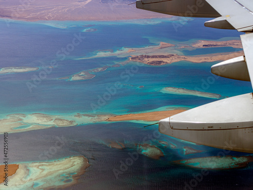 Aerial view above the clouds and sky  Inspiration concept. Travel freedom by air. Flight  view from the airplane to tropical sea with corals. Turbo-jet aircraft engine  transport 4k. Passenger airbus