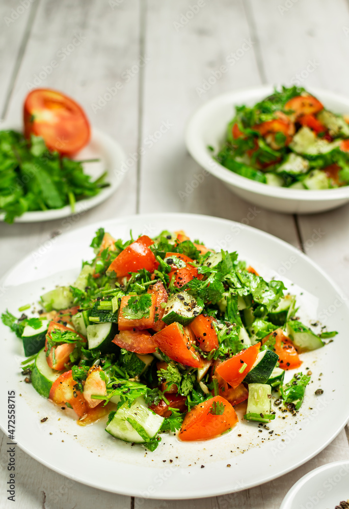 Mediterranean salad with tomatoes, cucumber, coriander, onions, olive oil and lemon in a white ceramic plate. Healthy vegetarian food, oriental and Mediterranean cuisine. Top view. Copy space. No.07