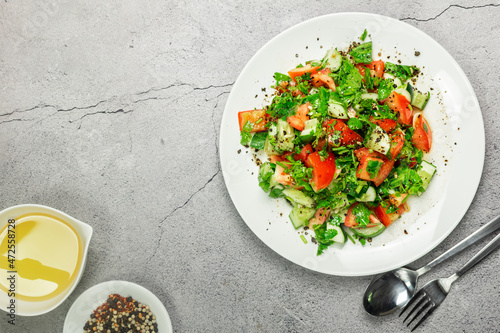 Mediterranean salad with tomatoes, cucumber, coriander, onions, olive oil and lemon in a white ceramic plate. Healthy vegetarian food, oriental and Mediterranean cuisine. Top view. Copy space. No.06