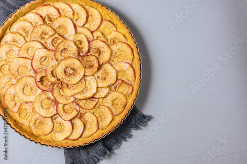 Top view of Classic french apple tart on a grey background with apples and cinnamon sticks