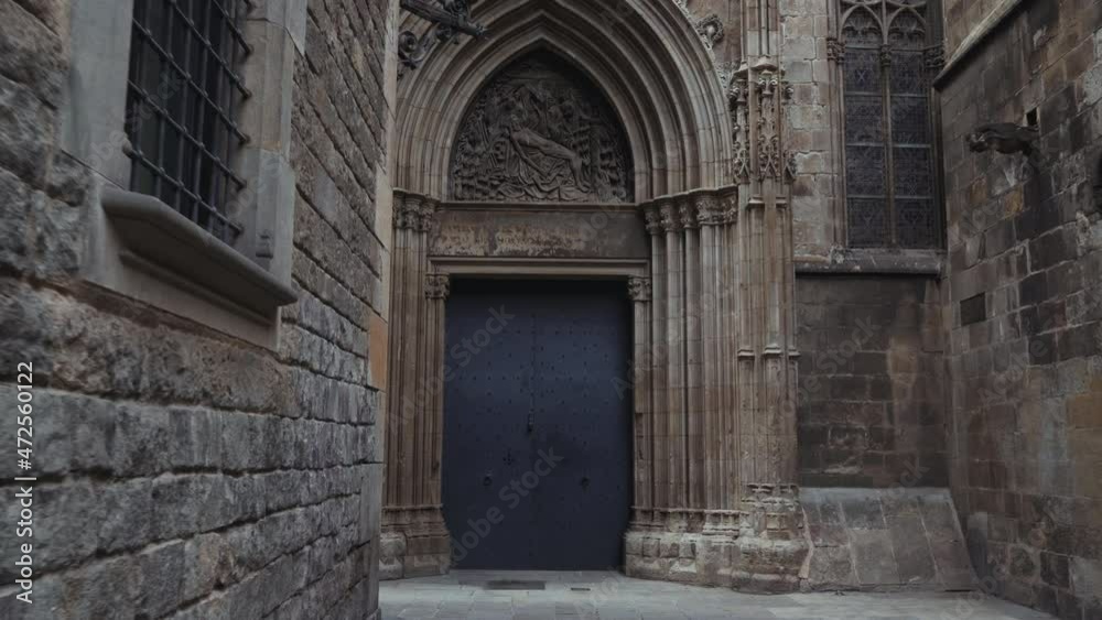 Barcelona - Carrer de la Pietat with barred windows and the stone walls of the Cathedral of Barcelona, moving towards an ancient door Barcelona - Carrer de la Pietat with barred windows and the stone walls of the Cathedral of Barcelona, moving towards an ancient door