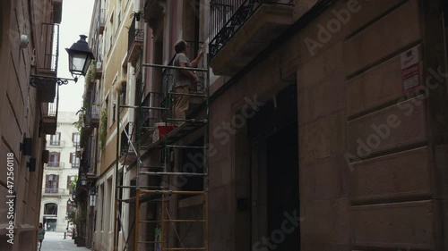 Barcelona - Gothic Quarter painter on scaffold works on exterior of ancient building photo