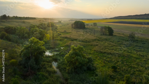 Top view of the countryside  river through fields and sun at sunset